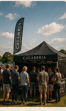 Calàbbria stall and flag at an outdoor festival, staff serving a queue of customers